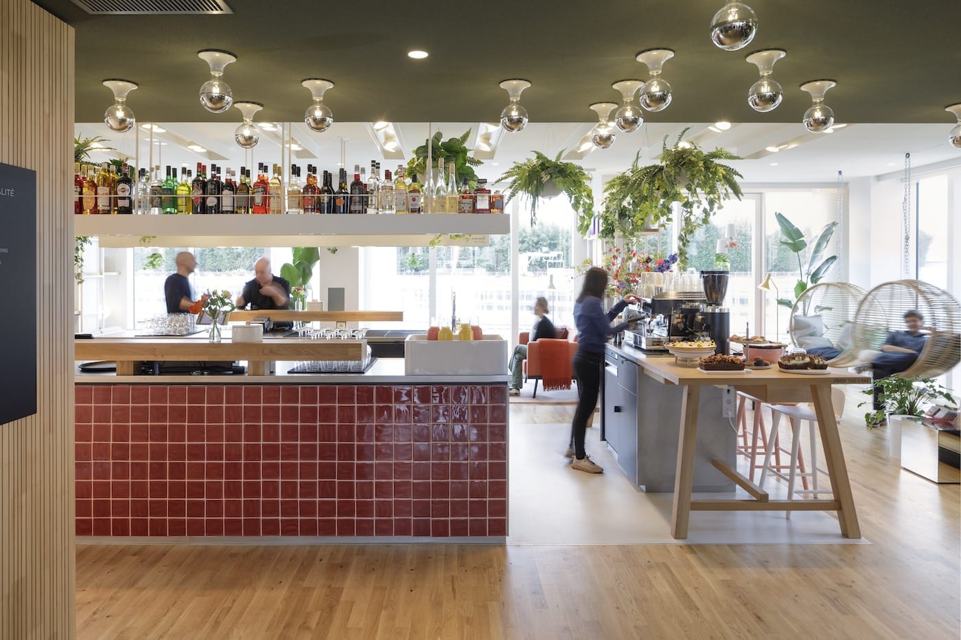 Bar parisien habillé de carrelage bordeaux, plantes et lumière tamisée